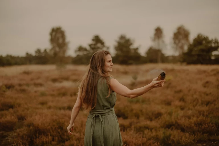 Romy Sauer - Reiki Ausbilderin und energetische Behandlungen - steht mit dem Rücken zu uns, dreht sich nach rechts und hält ein Räucherbündel am ausgestreckten Arm in der Hand